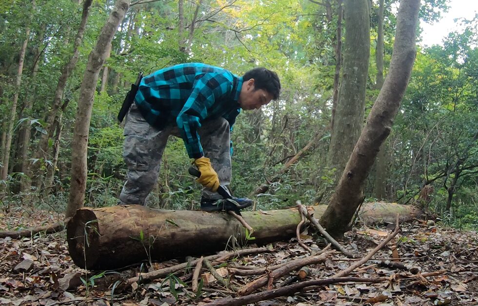 ゼロイチキャンプがノコギリをつかって、薪を切断している。