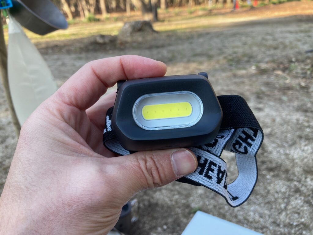筆者がダイソーのCOBヘッドライトを手に持っています。
