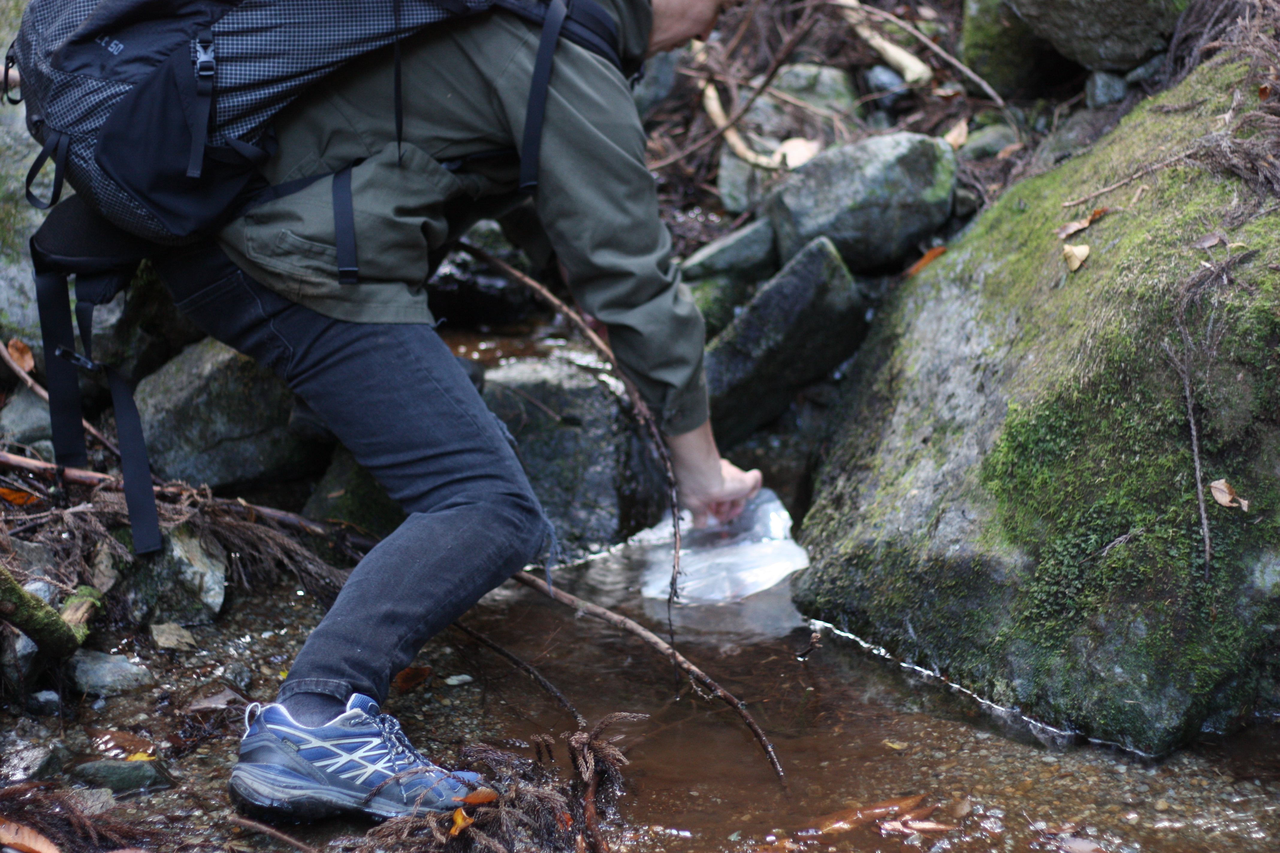 筆者が沢の水をZIP式の開口部のないウォーターバッグに水を汲み取っているところ。