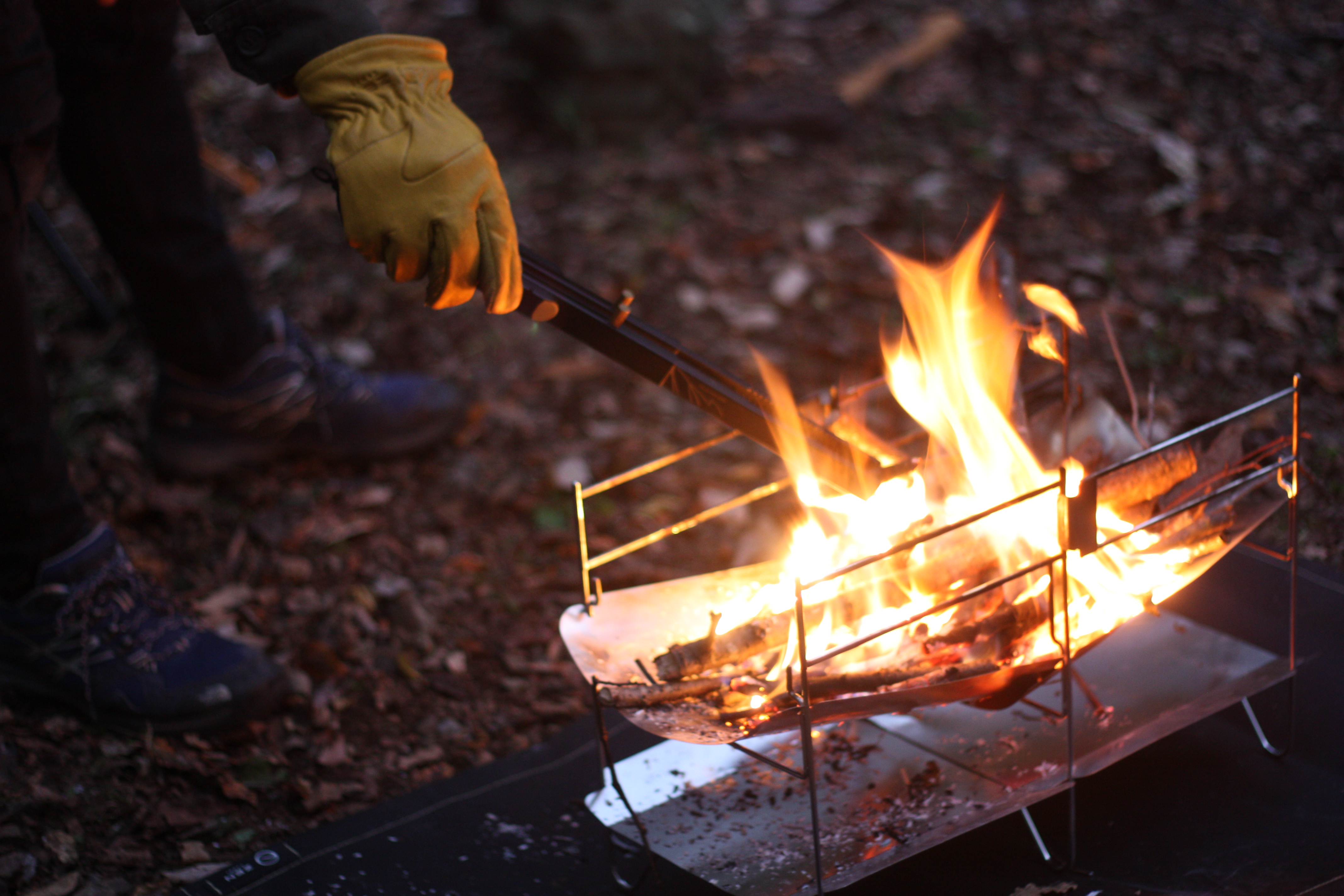 筆者がZEN Campsのキャンプ用グローブを装着し、薪をくべているものである