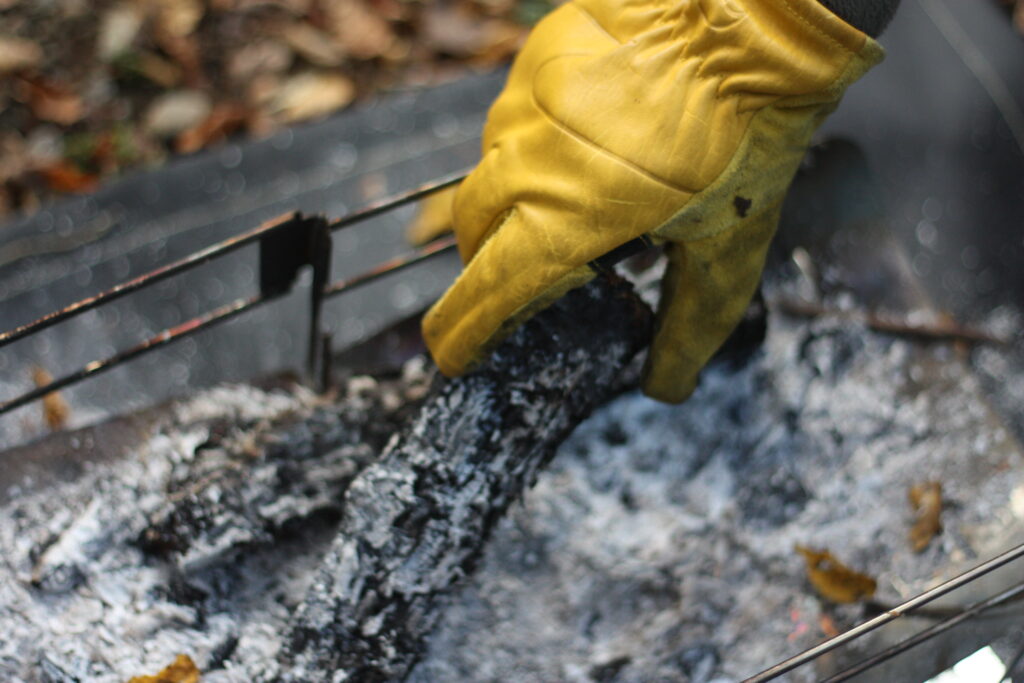 筆者がキャンプグローブをして、炭を持っているところ。