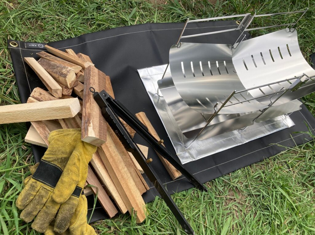 焚き火専用シート95×60㎝の空いているスペースに、薪やグローブ、火ばさみを置いたもの