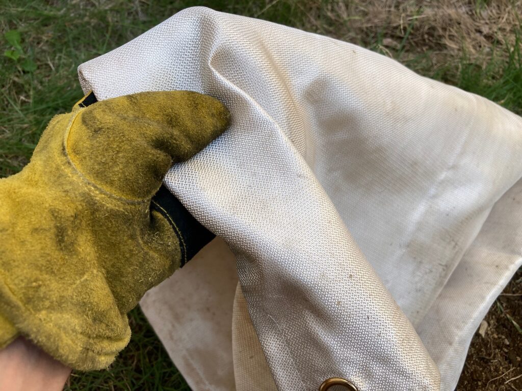 筆者がガラス繊維の焚き火シートを手に持っている