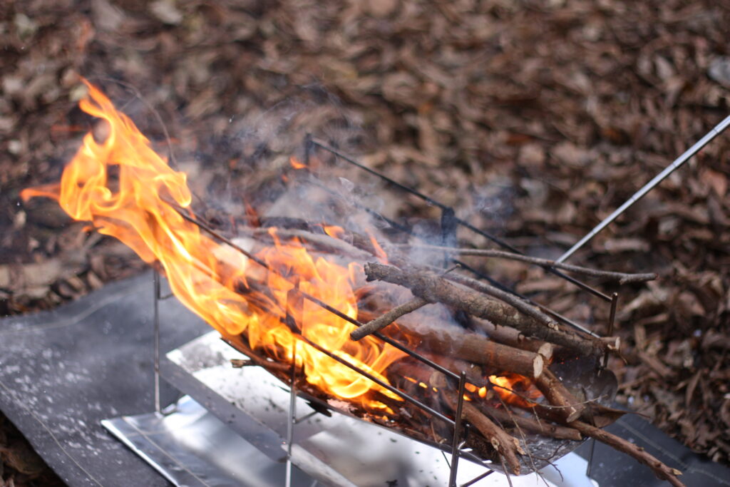 筆者が火吹き棒で焚き火の着火をしているところ
