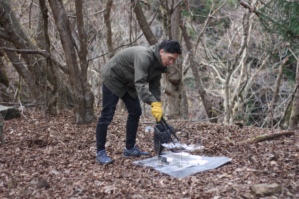 筆者が火ばさみをつかって、焚き火の処理をしているところ