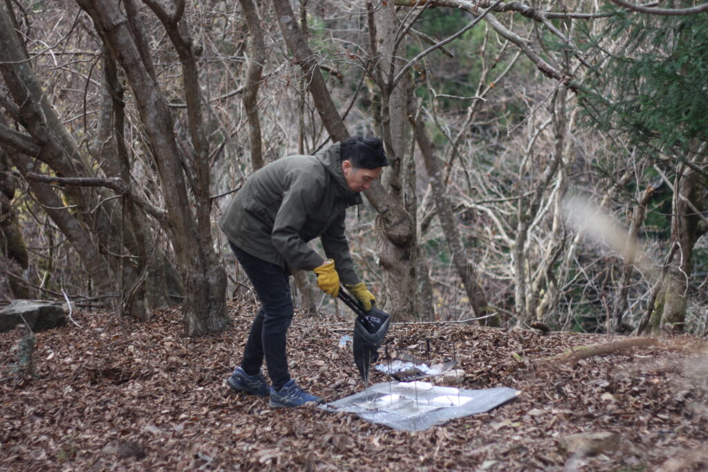 筆者が火ばさみと火消し袋をつかって、焚き火処理をしているところ