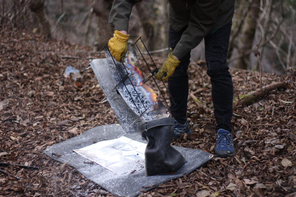 筆者が焚き火台NT FIRE STANDの細かい灰を捨てている